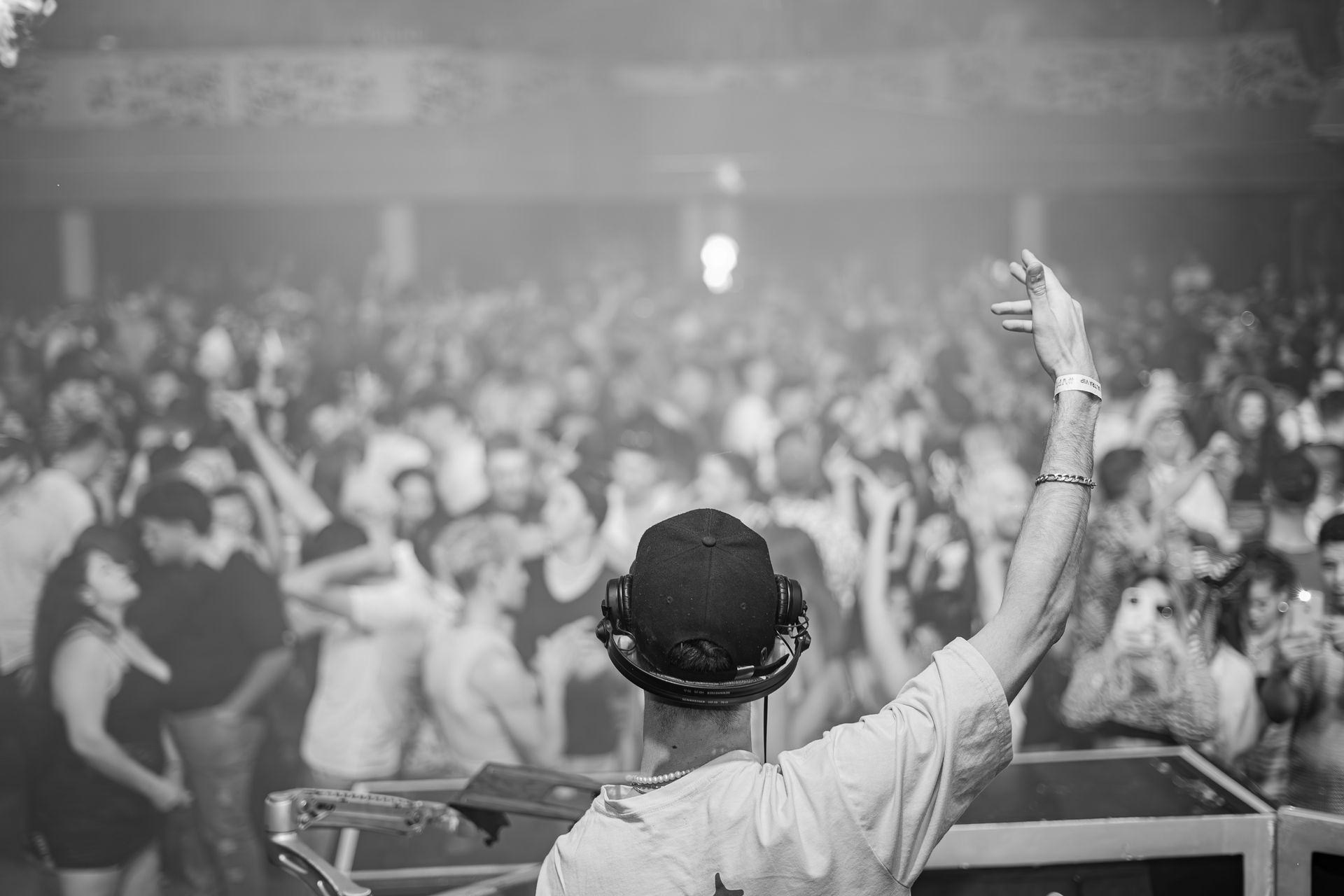 DJ with hand raised over a packed dance floor